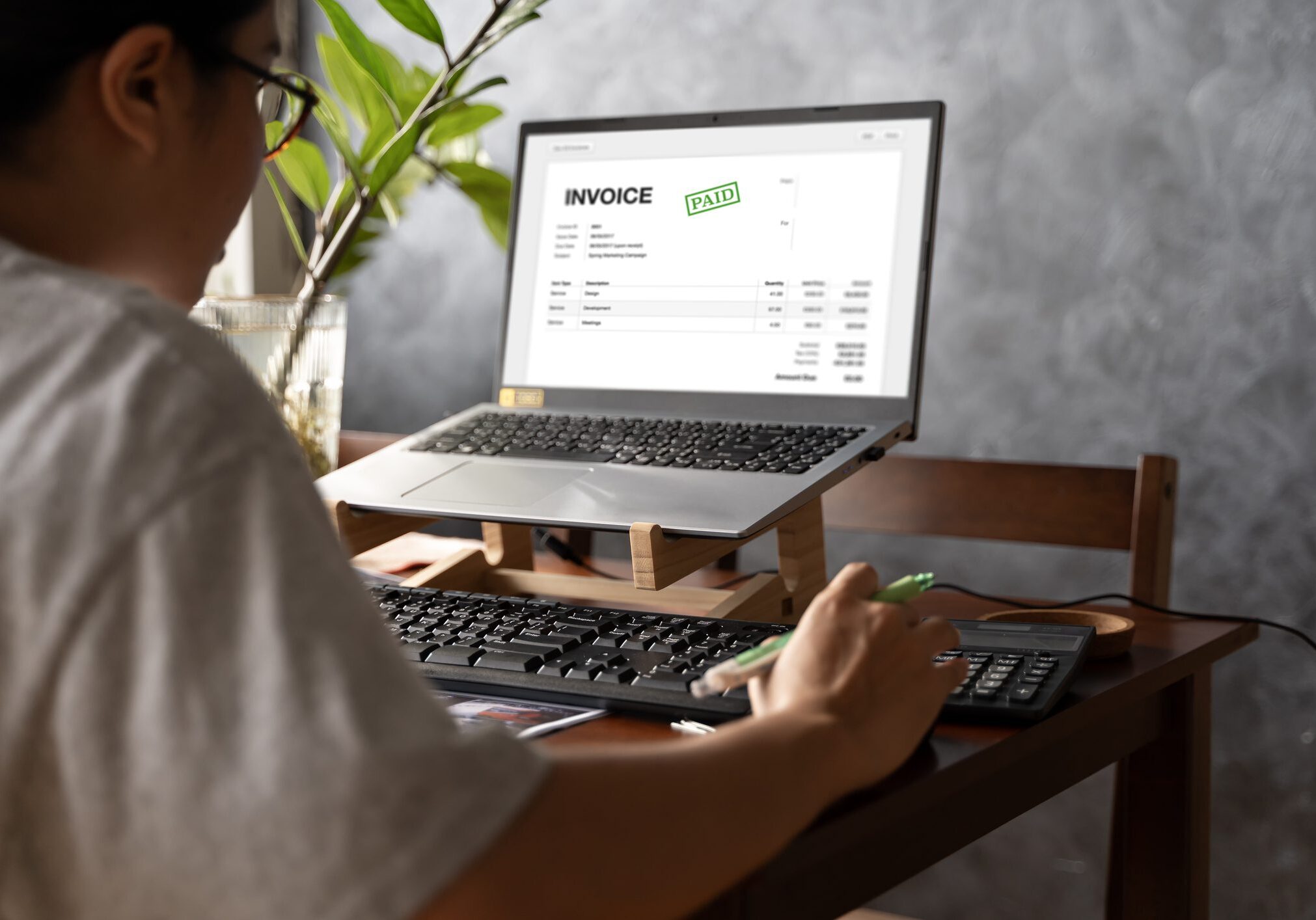 Person working at desk with paid invoice.